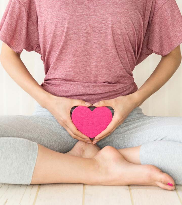 A woman holding a pink heart shape over her lower abdomen